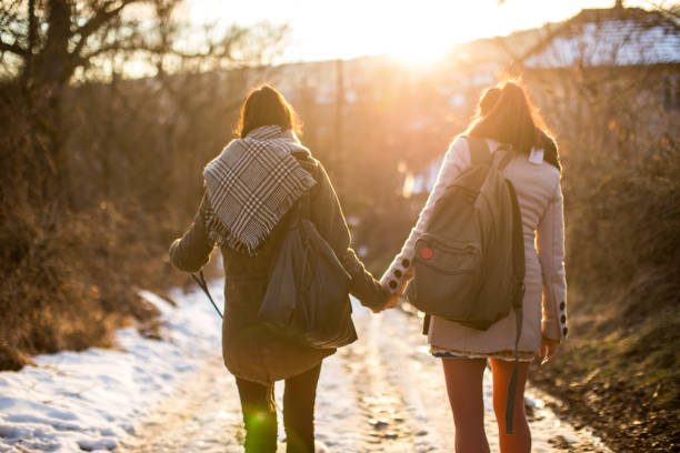 2 women waking hand in hand in winter landscape