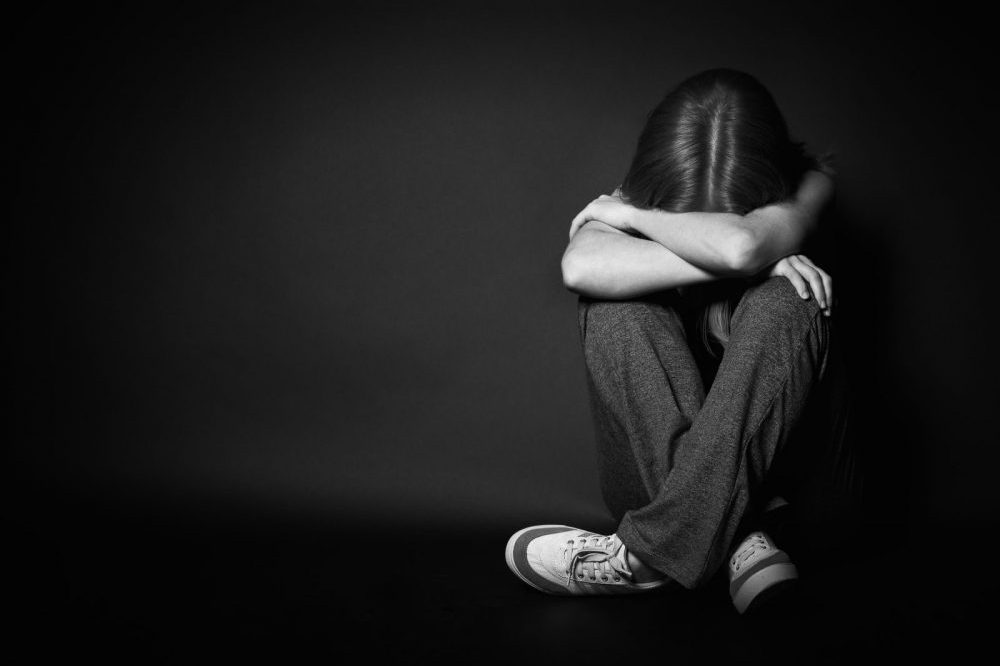 depressed girl sitting with her head down