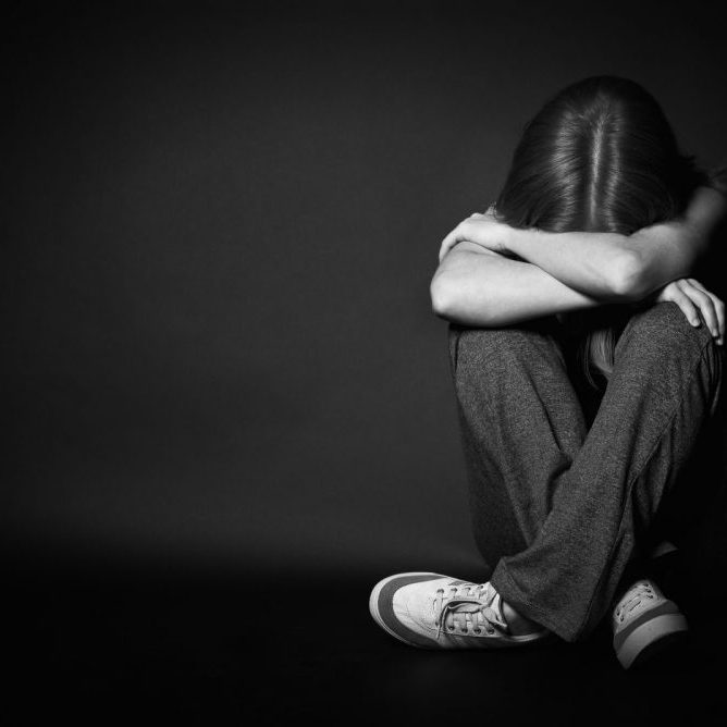 depressed girl sitting with her head down