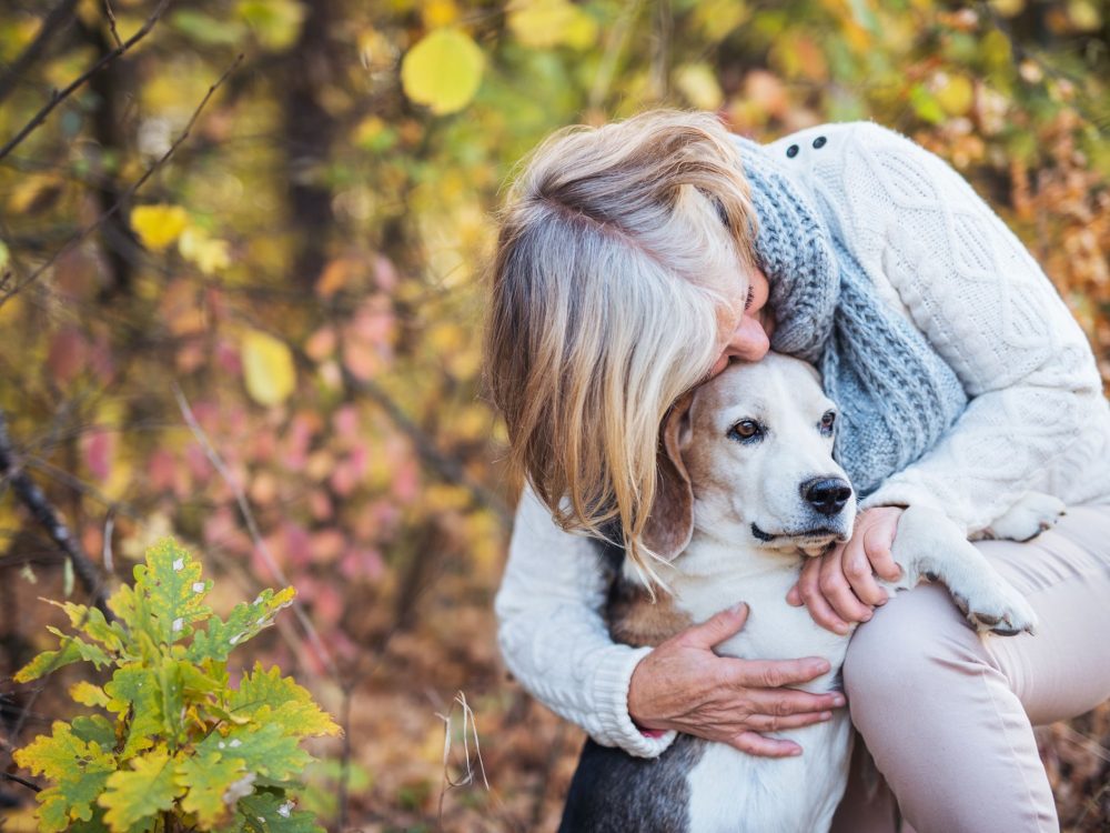 Older woman cuddling her older dog 