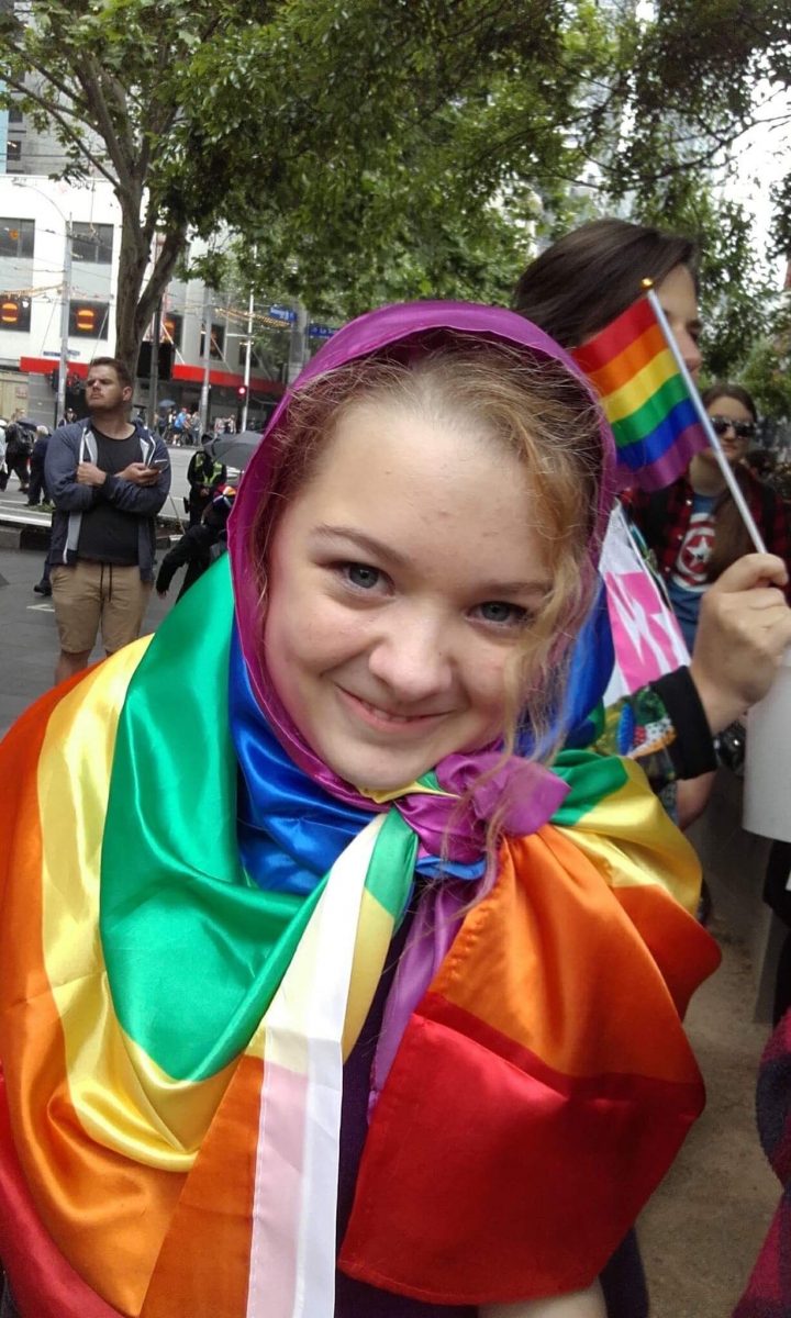 girl wrapped into a rainbow flag