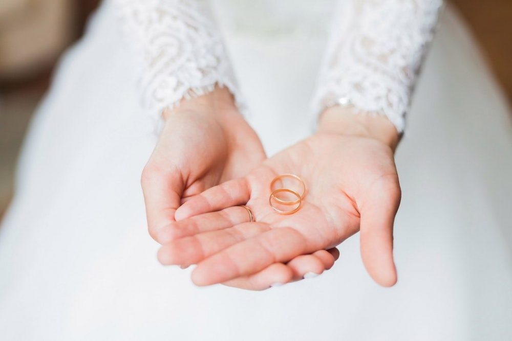 Bride holding 3 wedding rings