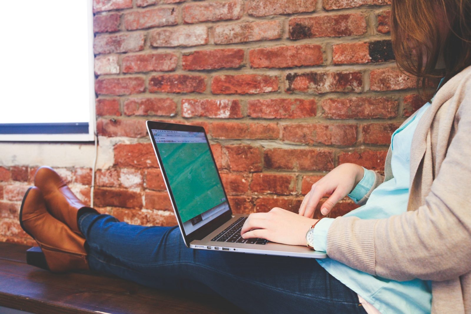 woman sitting on a bench using a laptop