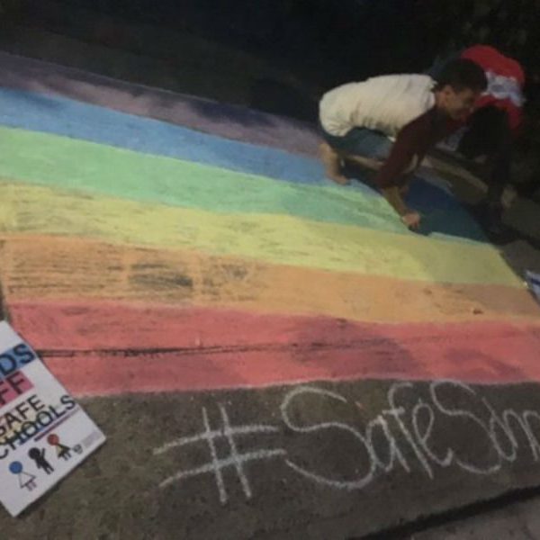 Person chalking Rainbow flag on footpath