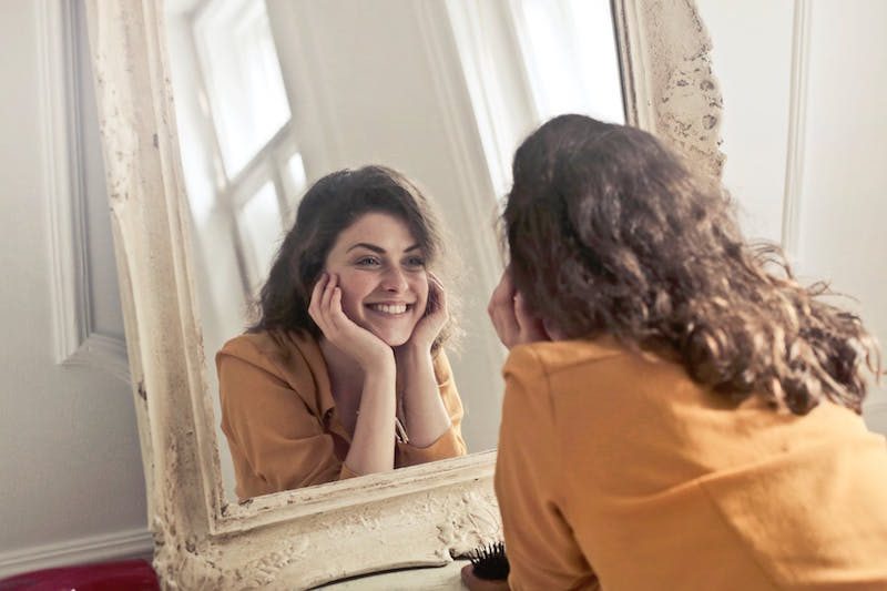 woman looking into mirror smiling 