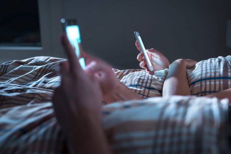 couple using mobile phone in bed