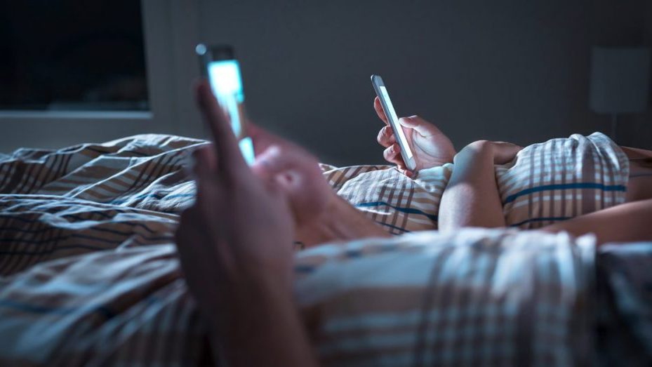 couple using mobile phone in bed
