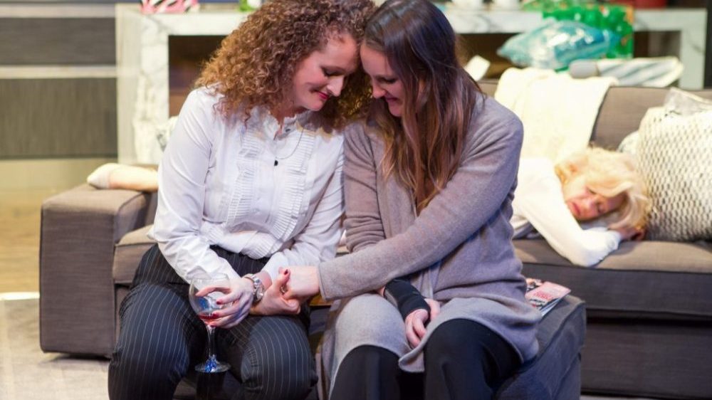 lesbians sitting on sofa holding hands