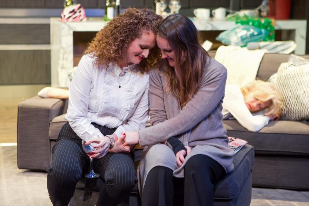 lesbians sitting on sofa holding hands