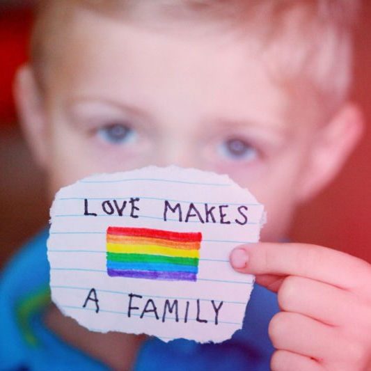 Child holding a note: love makes a family