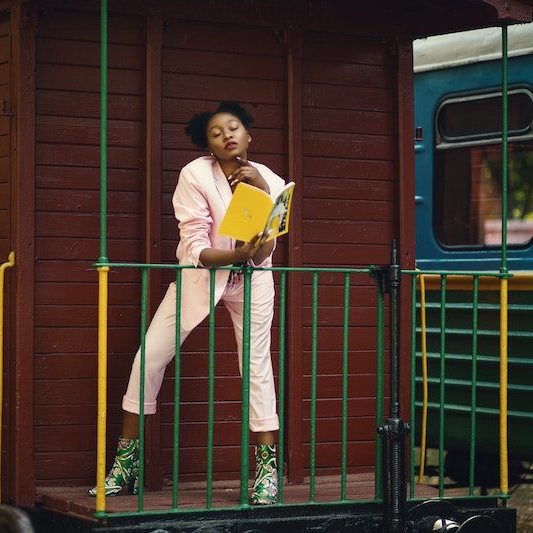 black woman reading book next to a train