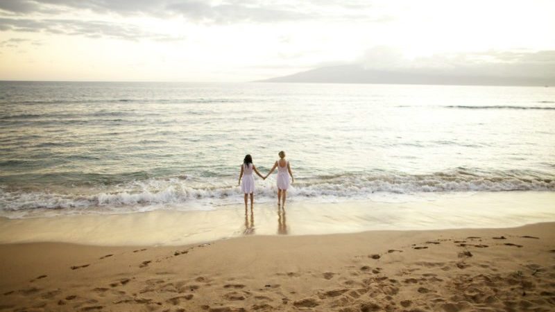 2 women walking on the beach in sunset