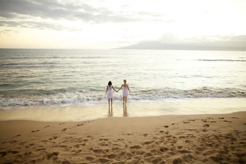 2 women walking on the beach in sunset
