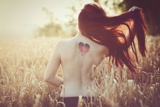 woman from behind with love heart tatoo on her back