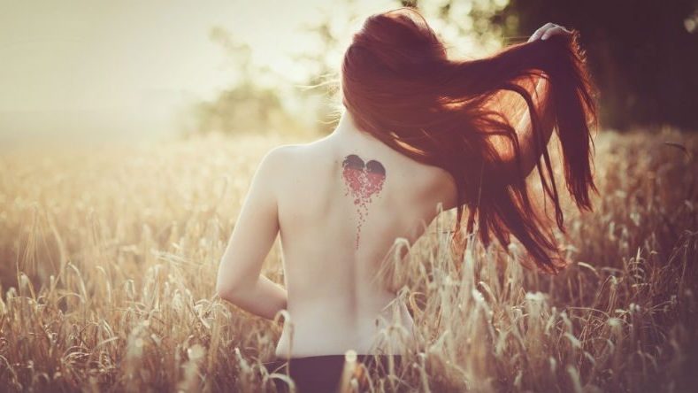 woman from behind with love heart tatoo on her back