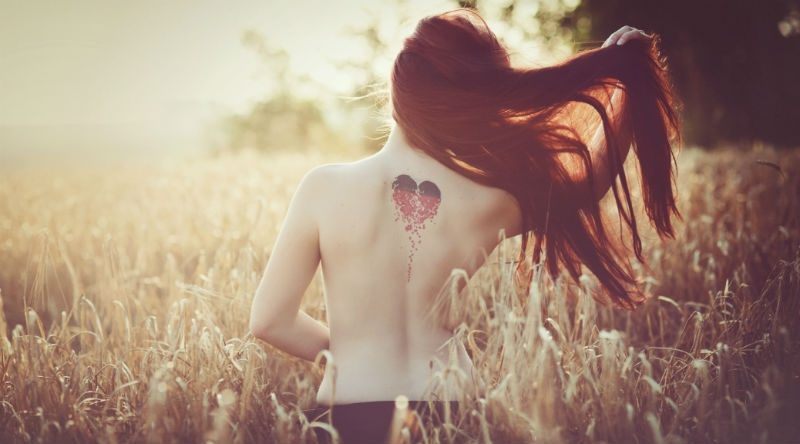 woman from behind with love heart tatoo on her back