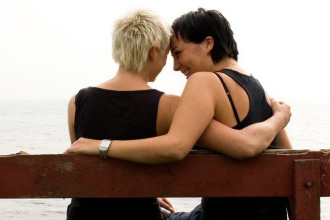 2 women sitting on bench by the water