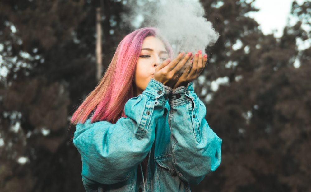 women with pink long hair blows dust from her hands 