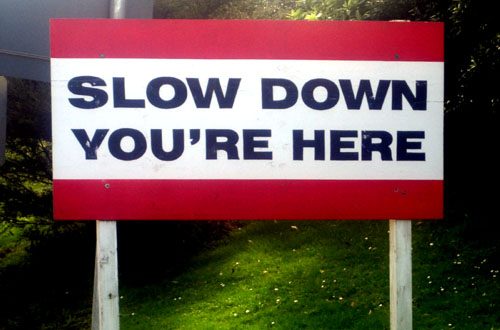 Street Sign: Slow Down you're here'