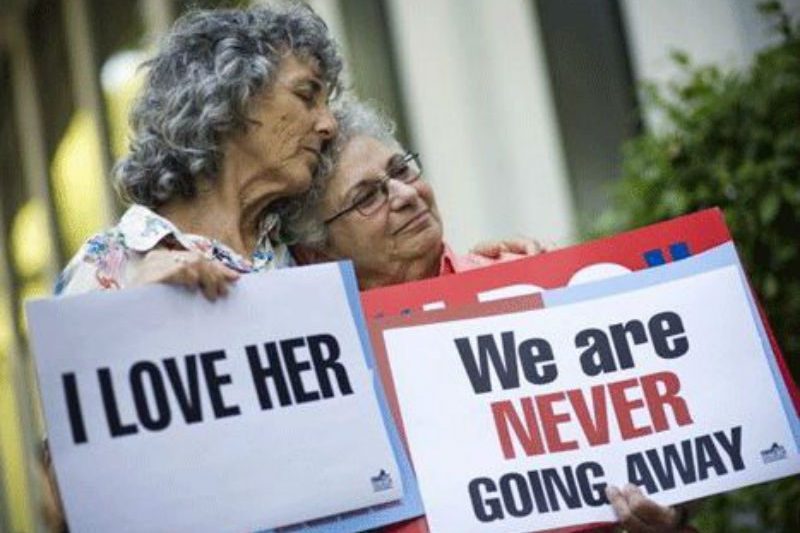 2 older Lesbians holding up signs