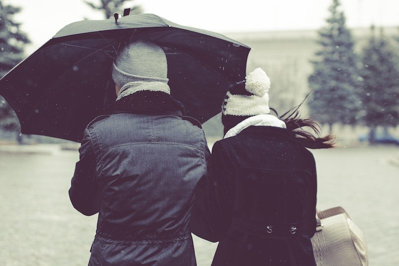 2 people standing in rain with umbrella