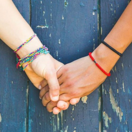 2 women with braclets holding hands