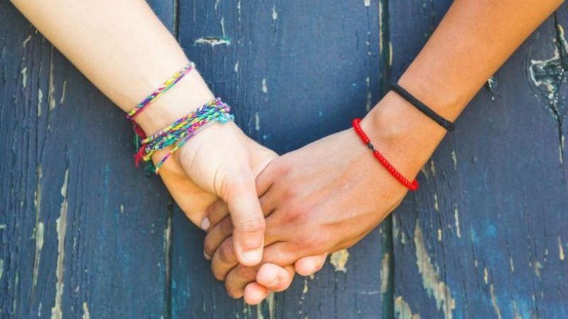 2 women with braclets holding hands