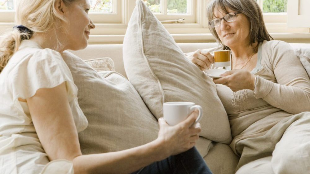 Older and younger woman talking on sofa