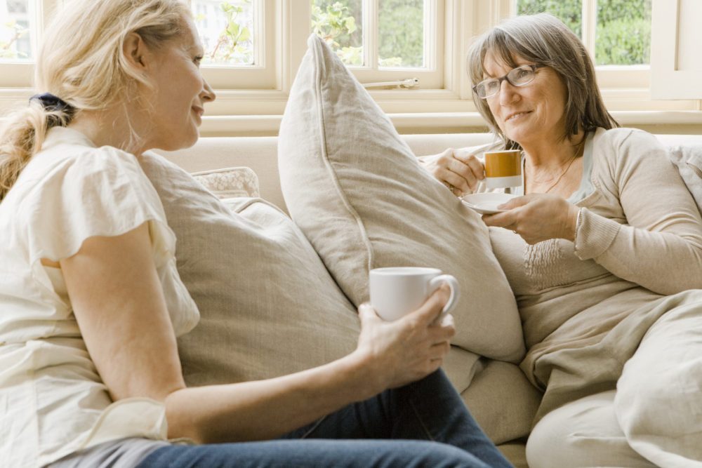 Older and younger woman talking on sofa