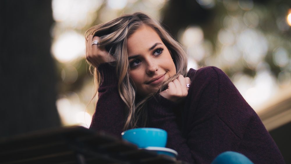 Young woman smiling over cup of coffee