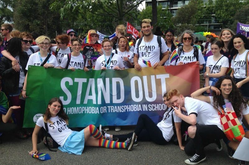 demostrators stand behind stand out banner