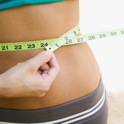 woman putting tape measure around her waist 