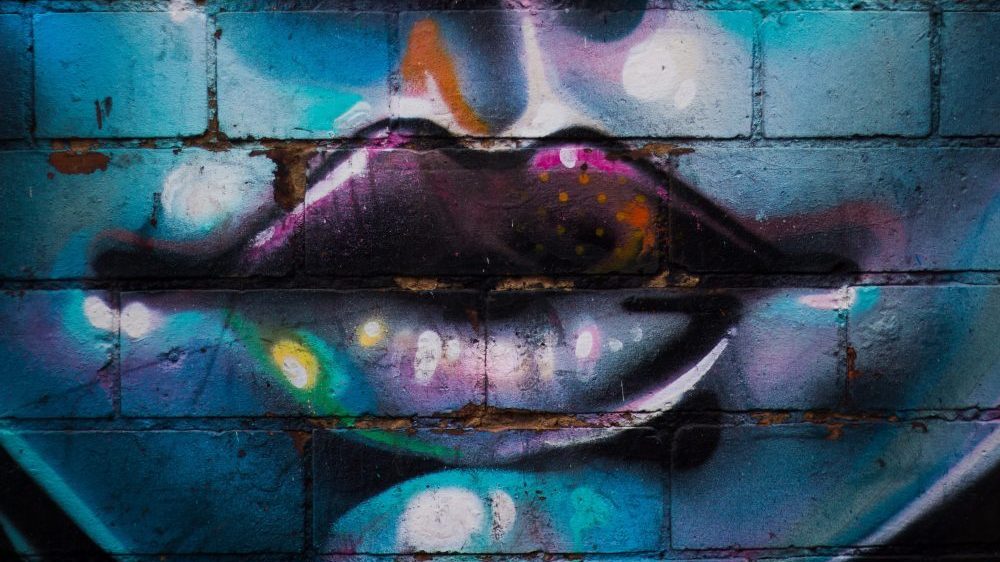 graffiti of womens face on blue brick wall