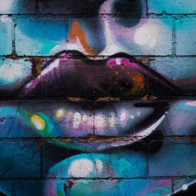 graffiti of womens face on blue brick wall