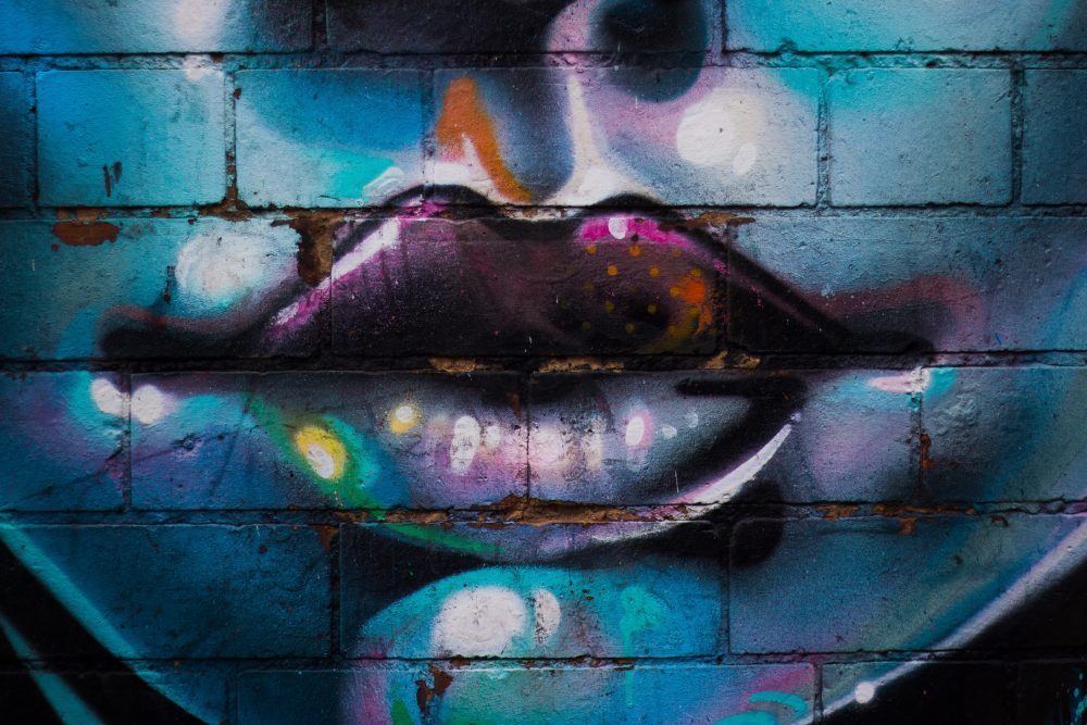 graffiti of womens face on blue brick wall