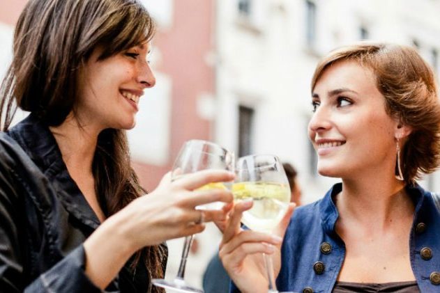 2 women drinking out of wine glass