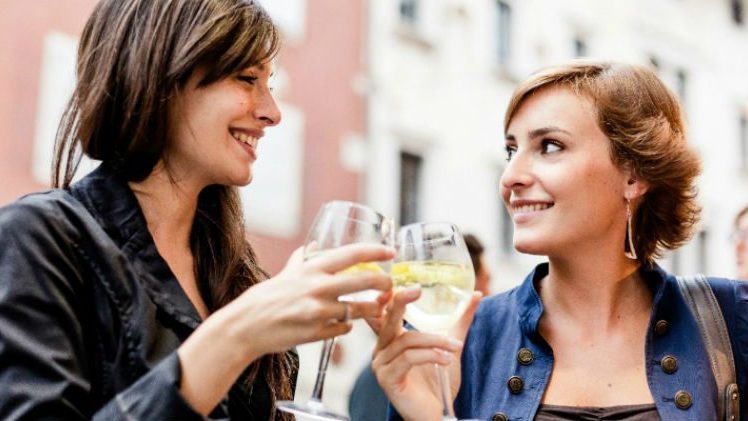 2 women drinking out of wine glass