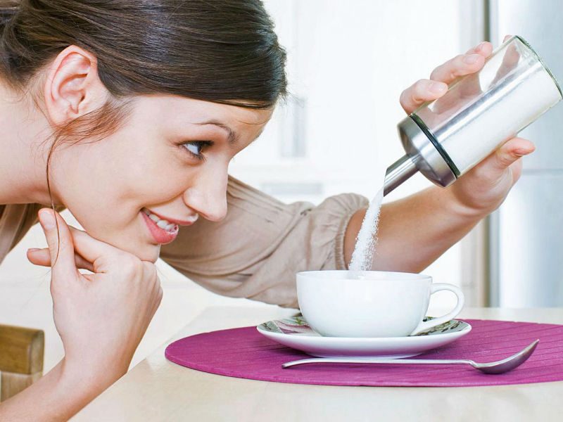 woman puring sugar into cup
