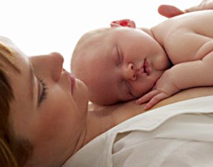 newborn baby lying on top of woman