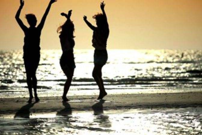 3 women dancing during sunset at the beach