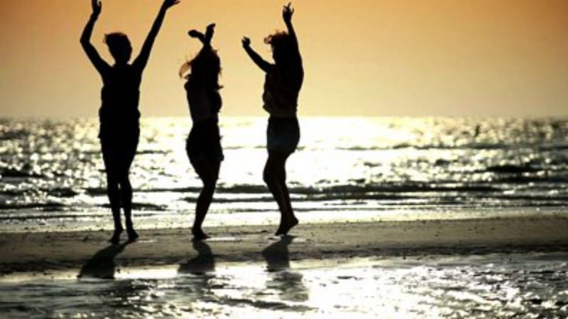 3 women dancing during sunset at the beach