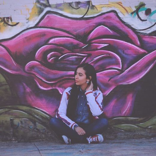 woman sitting in front of graffity wall