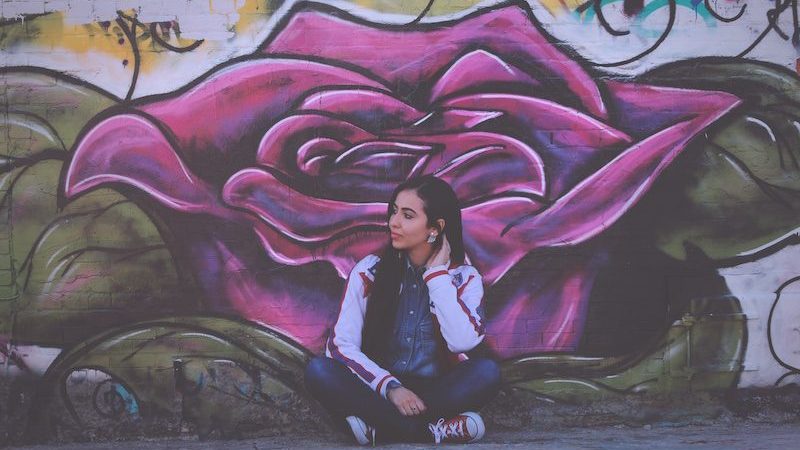 woman sitting in front of graffity wall