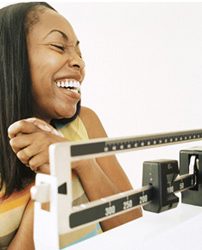 woman of colour laughing in front of a scale