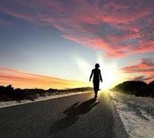 woman walking into sunset on a road