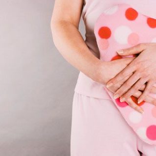 woman holding hot waterbottle in front of stomach