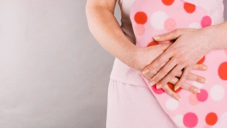 woman holding hot waterbottle in front of stomach