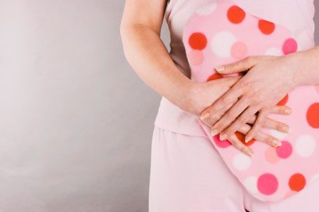 woman holding hot waterbottle in front of stomach