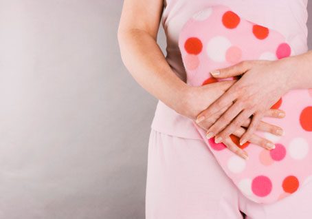 woman holding hot water bottle in front of stomach