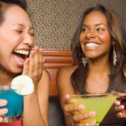 2 young women laughing over cocktails